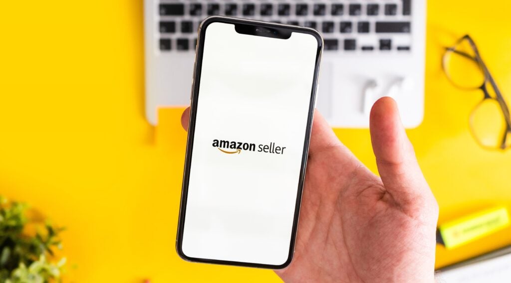Person holding a smartphone with the Amazon seller logo displayed on the screen