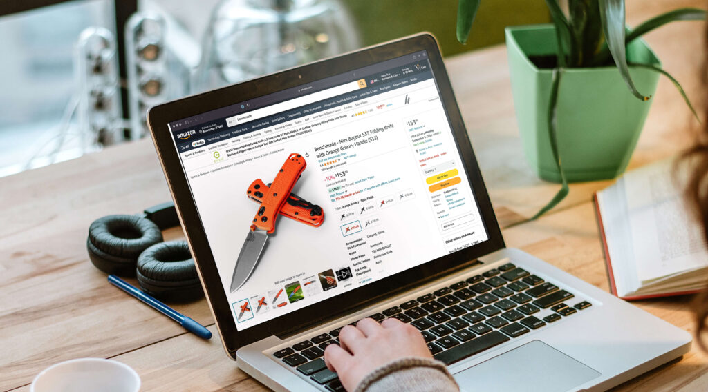Person working on a laptop with a Benchmade Amazon product page displayed on the screen