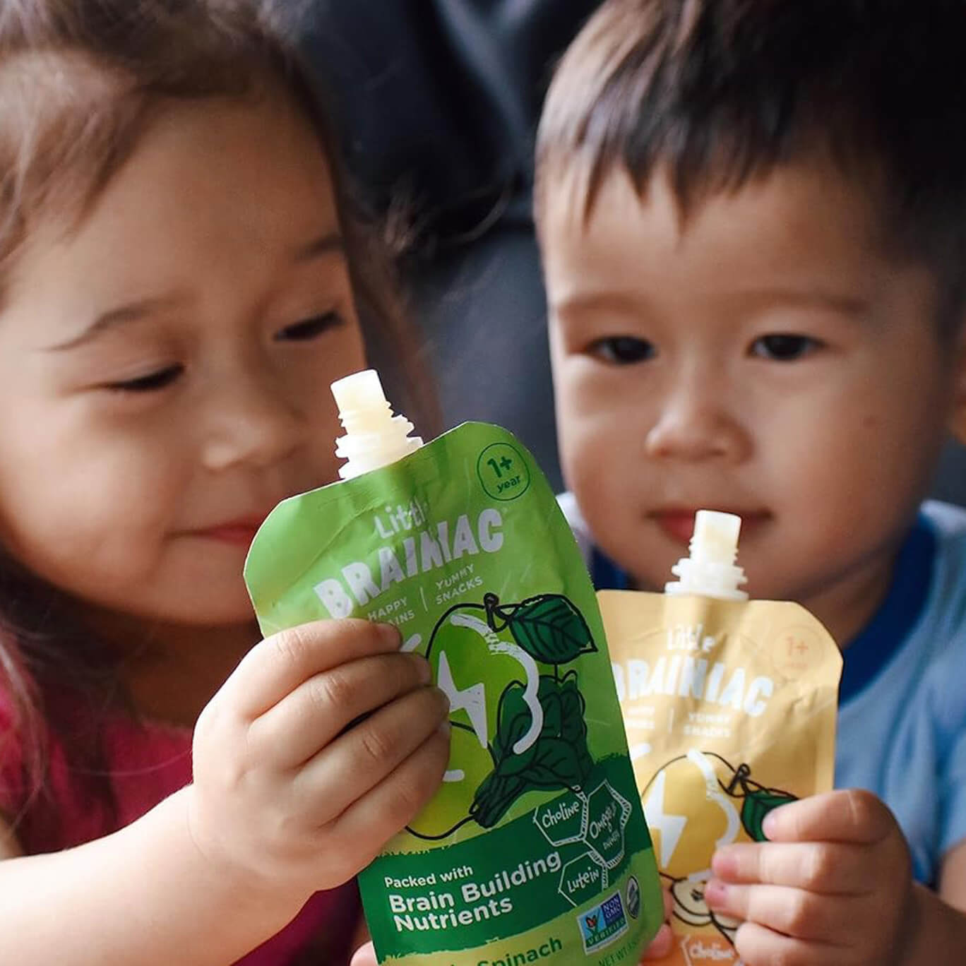 Two toddlers holding Little Brainiac food pouches